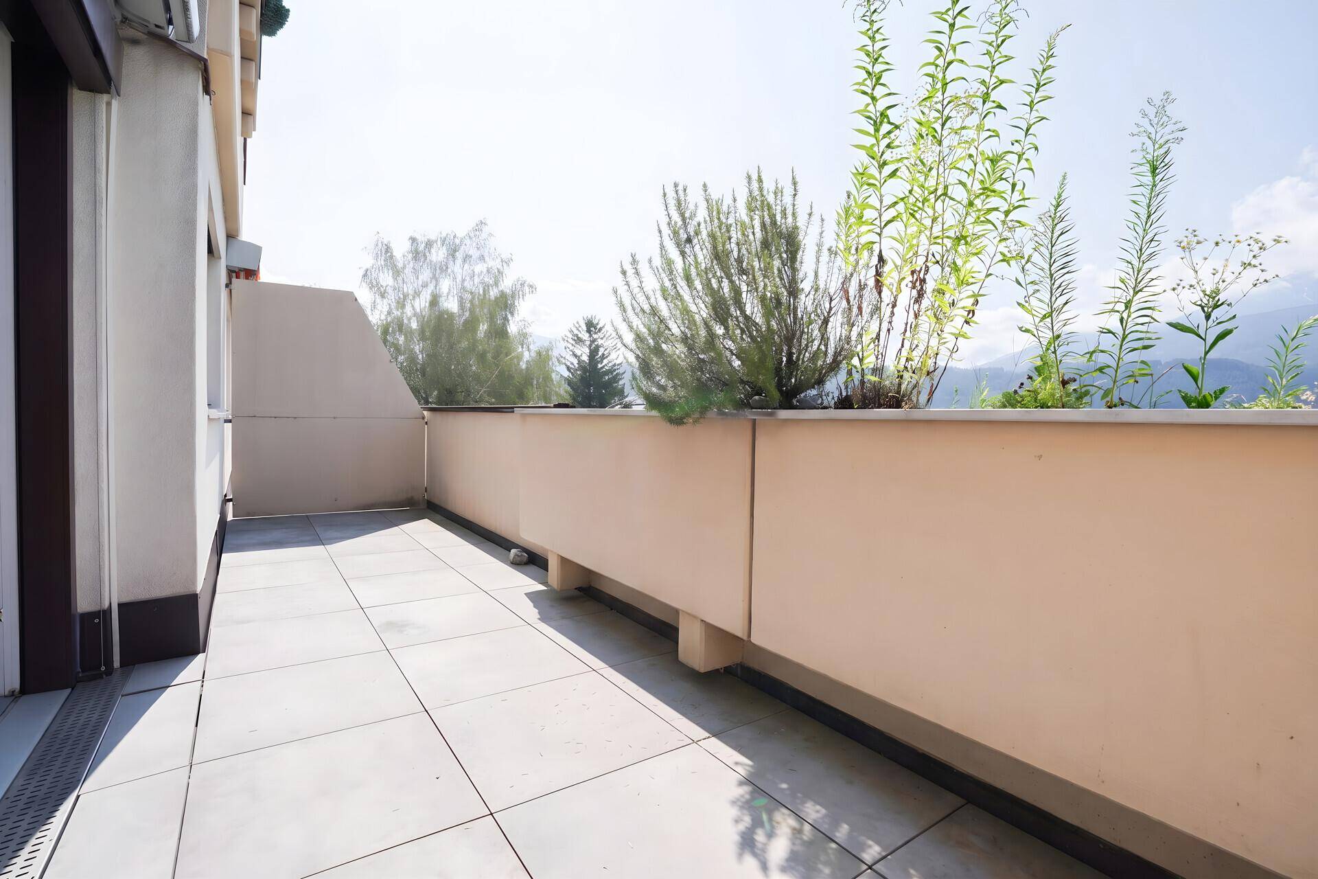 Sonniger Balkon mit Fliesenboden und Pflanzen, ideal für entspannte Stunden im Freien.