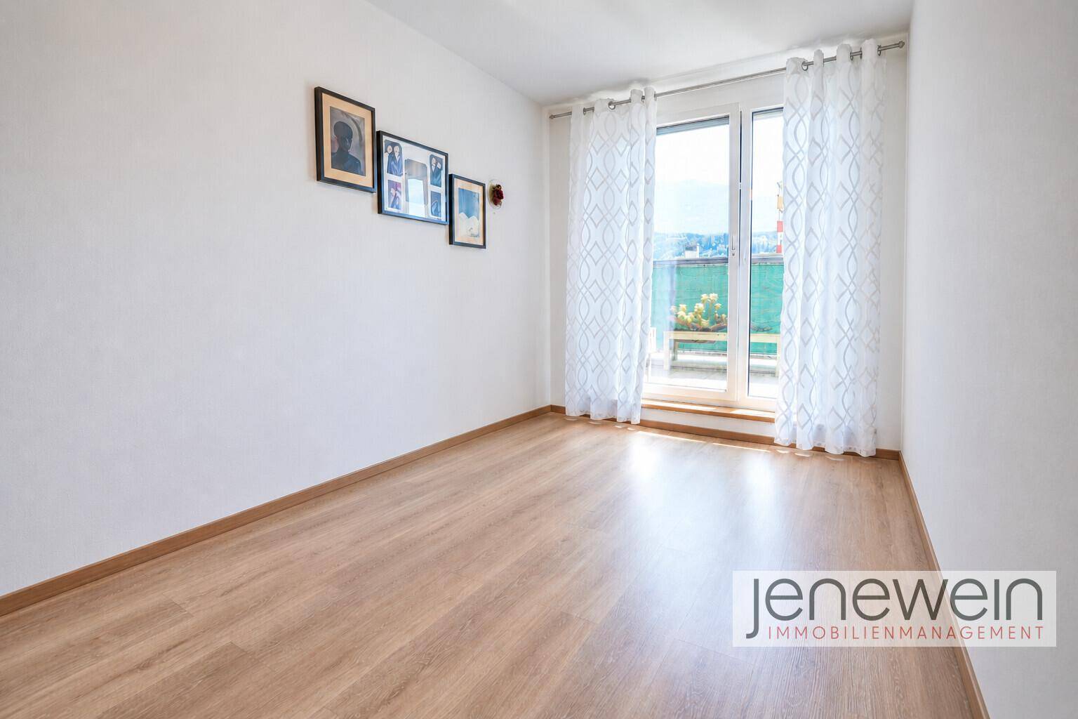 Helles Zimmer mit Laminatboden und Zugang zu einem Balkon oder einer Terrasse.