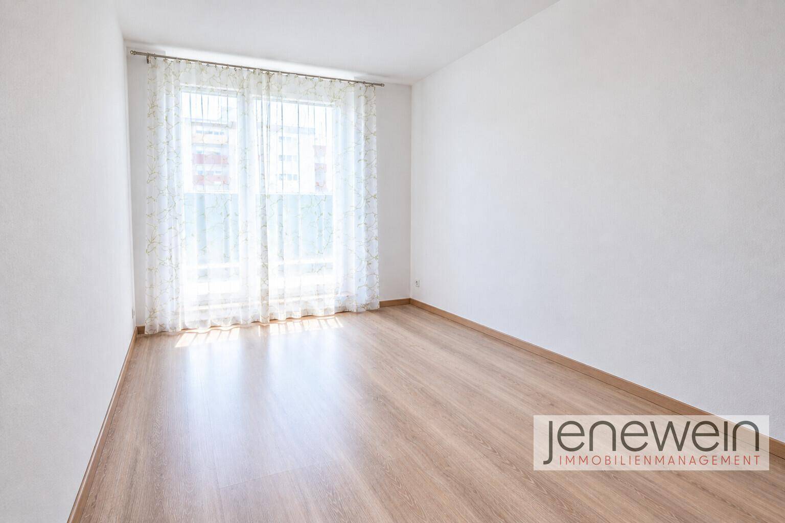 Leeres, helles Zimmer mit Laminatboden und großen Fenstern für viel Tageslicht.