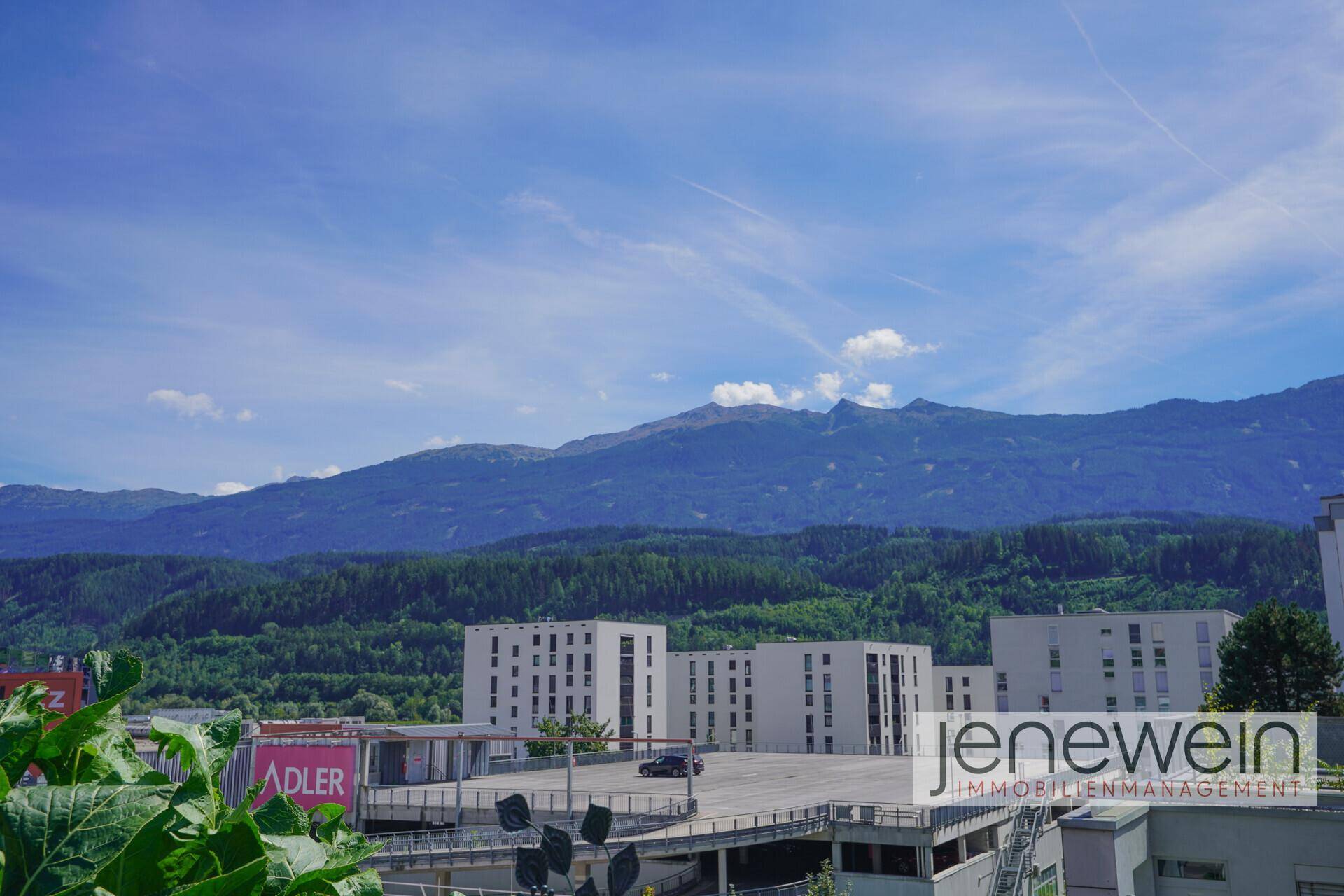 Panoramablick auf die bewaldeten Berge und städtische Gebäude in der Ferne.