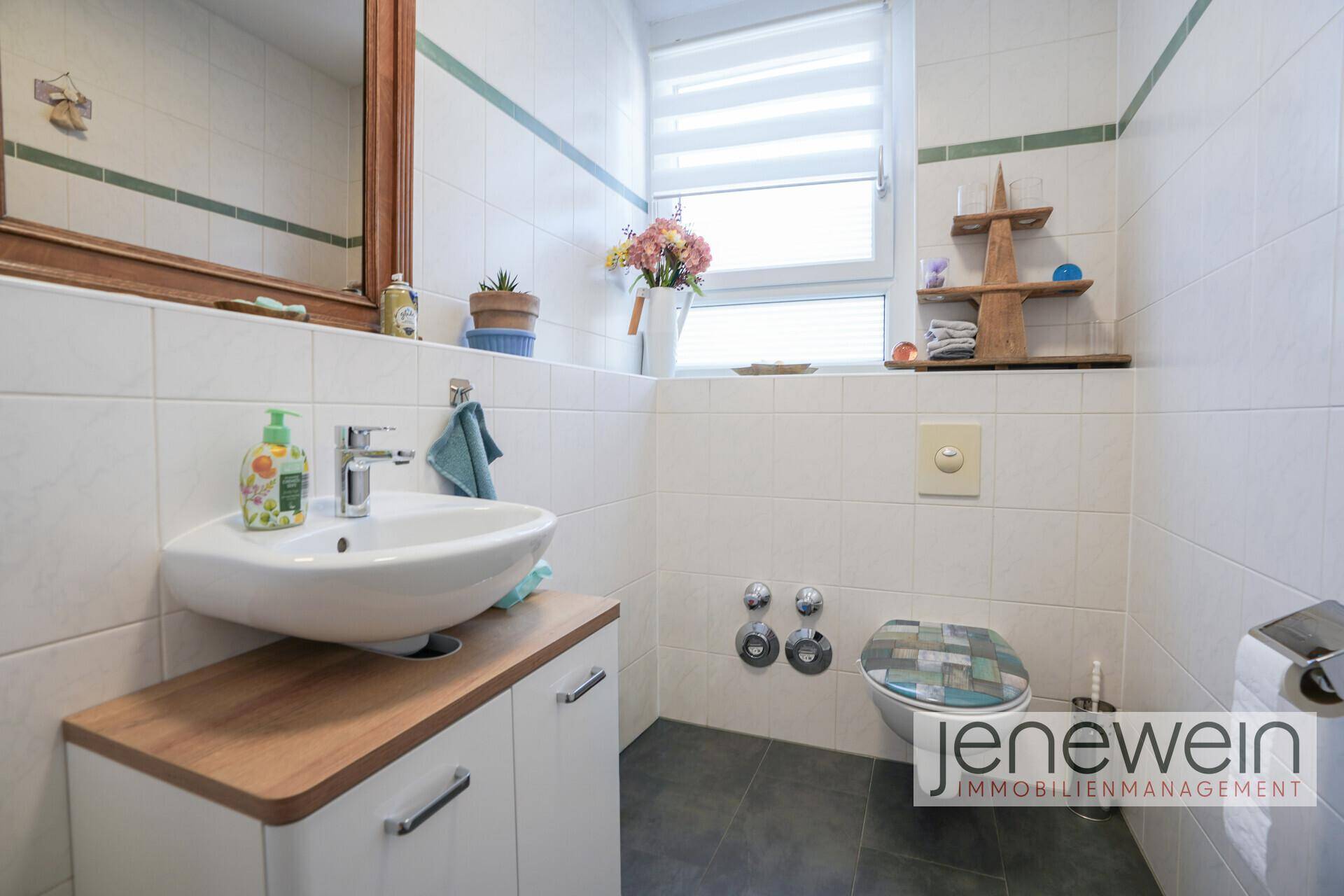 Helles Gäste-WC mit Waschbecken, Toilette und Fenster für natürliche Belüftung.