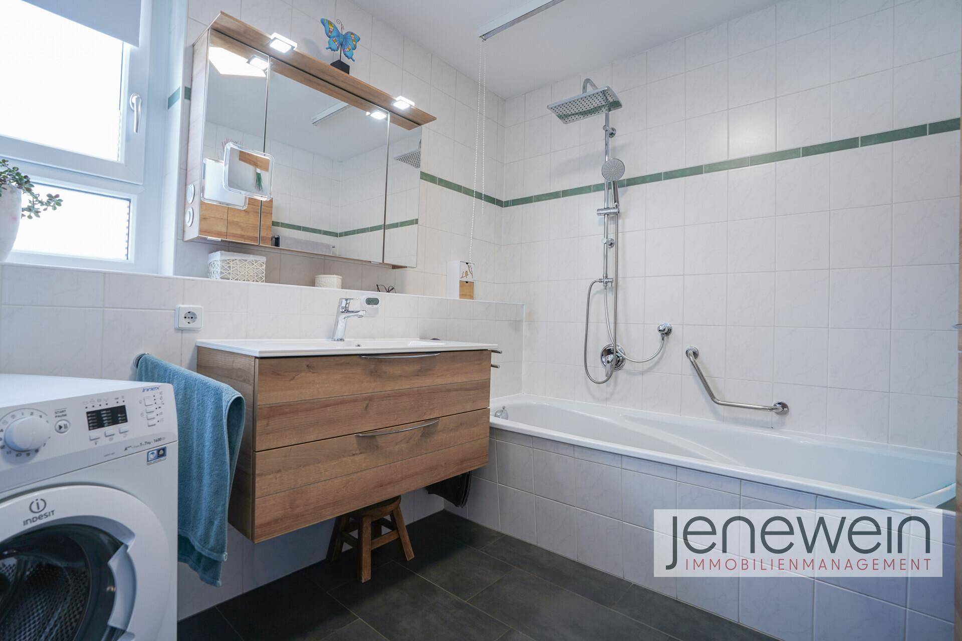 Modernes Badezimmer mit Badewanne, Dusche, Waschbecken und Waschmaschine.