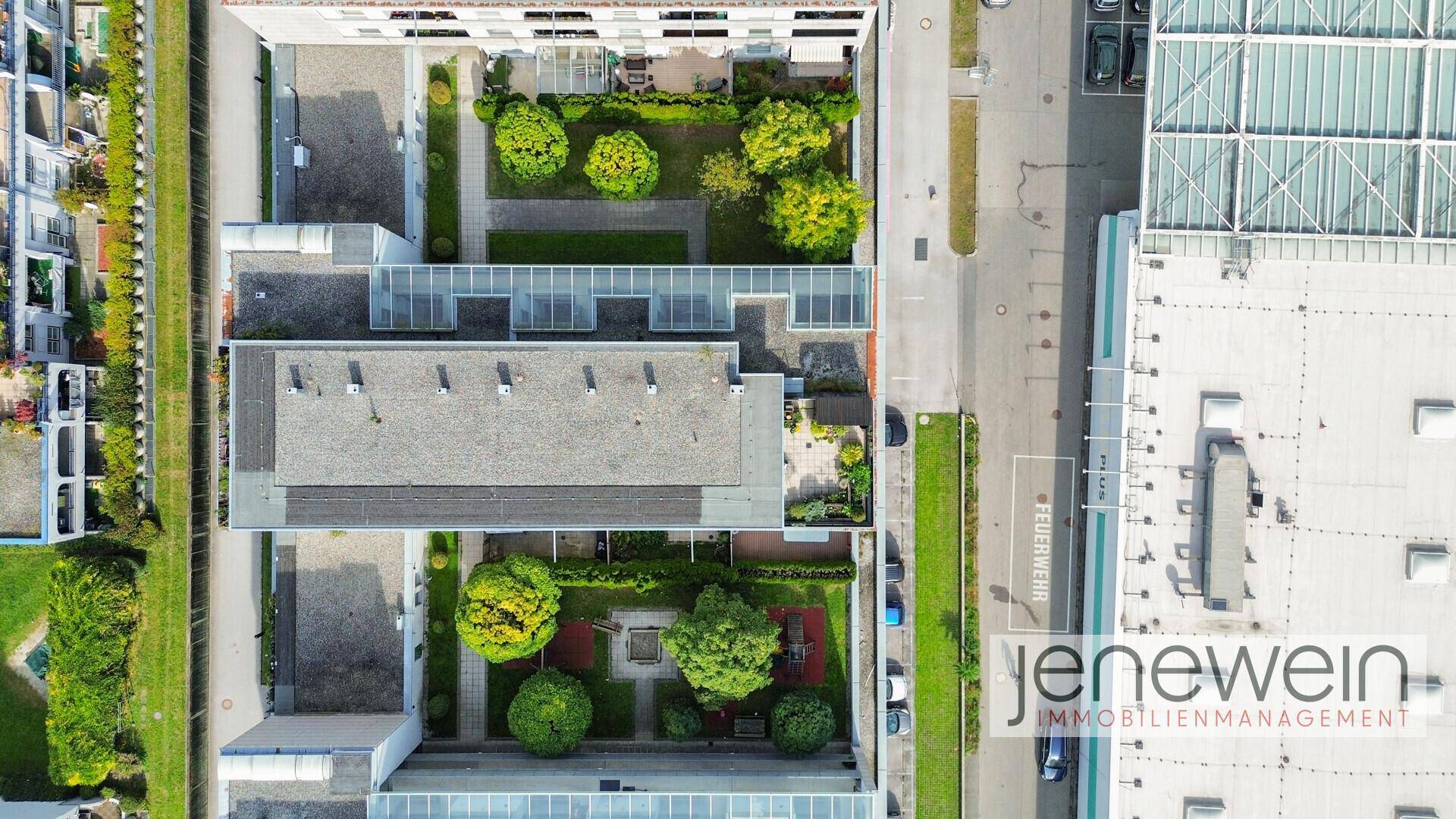 Vogelperspektive eines Wohnkomplexes mit begrünten Innenhöfen und angrenzenden Straßen.