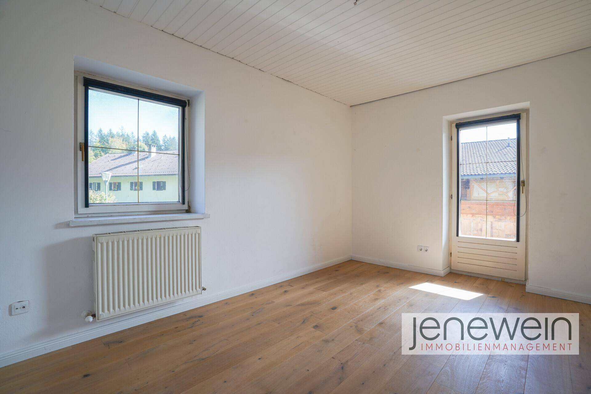 Geräumiges Schlafzimmer mit Holzboden, Fenster und Zugang zum Außenbereich.