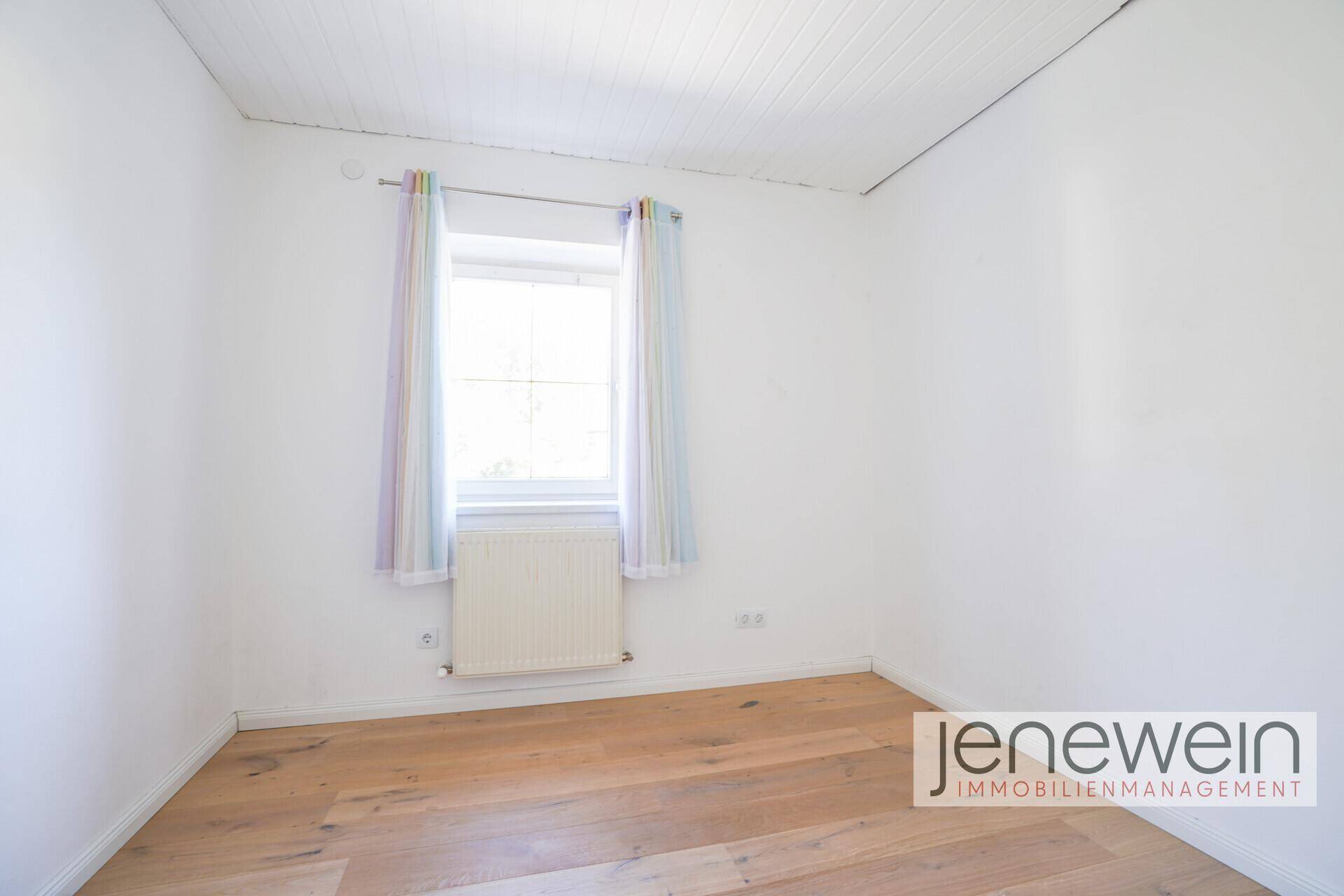 Helles Schlafzimmer mit Holzboden und Fenster, bereit zur individuellen Gestaltung.