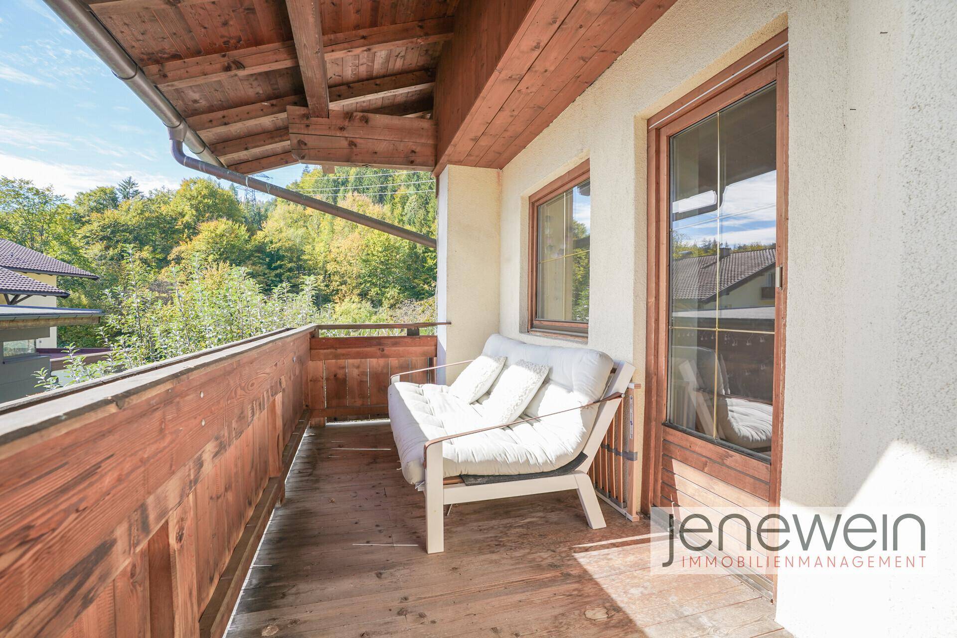 Gemütlicher Holzbalkon mit Sitzgelegenheit und Blick auf die grüne Umgebung.