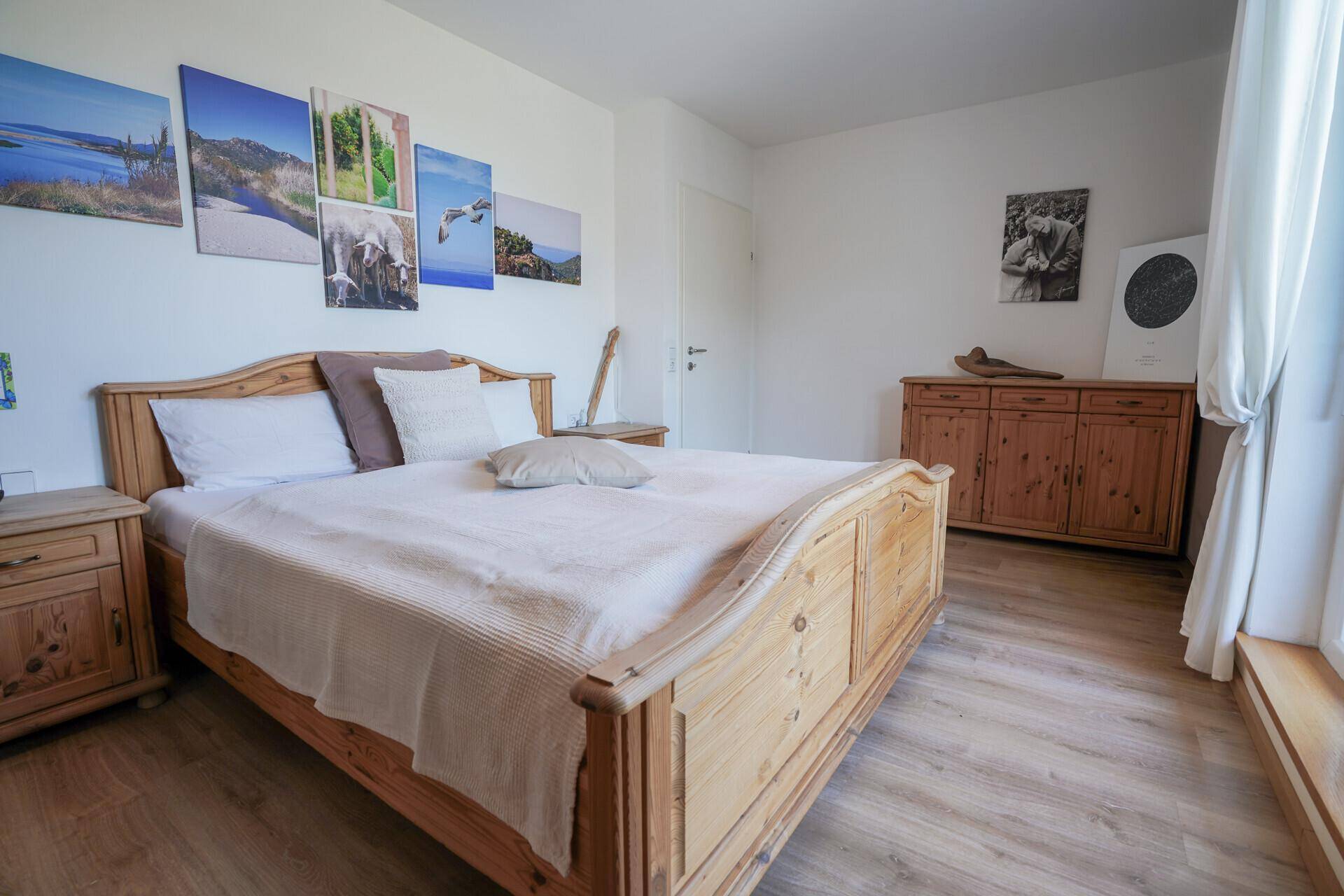 Schlafzimmer mit rustikalem Holzbett, Laminatboden und dekorativen Wandbildern.