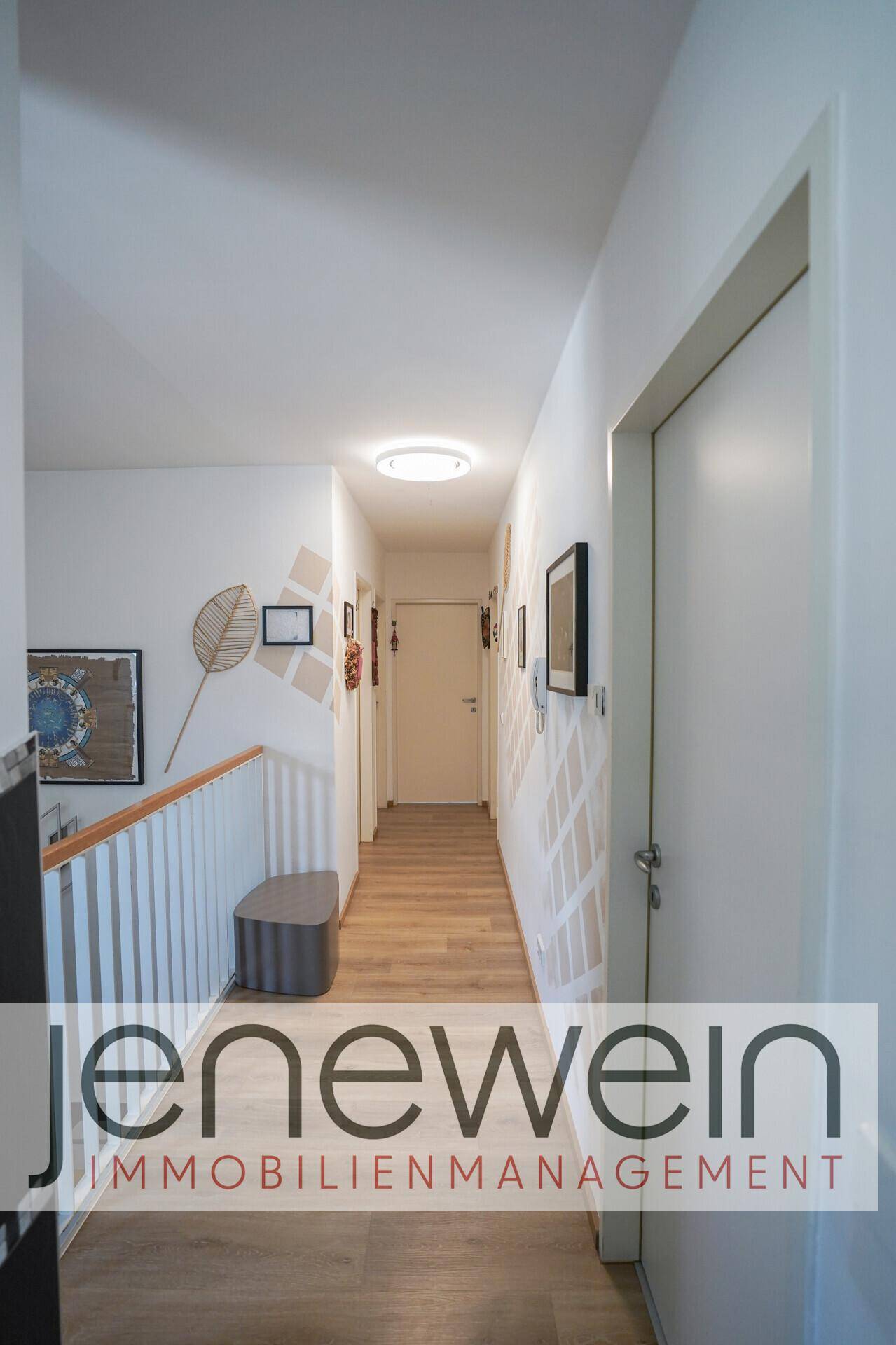 Heller Flur mit Laminatboden, weiß gestrichenen Wänden und Deckenleuchte.