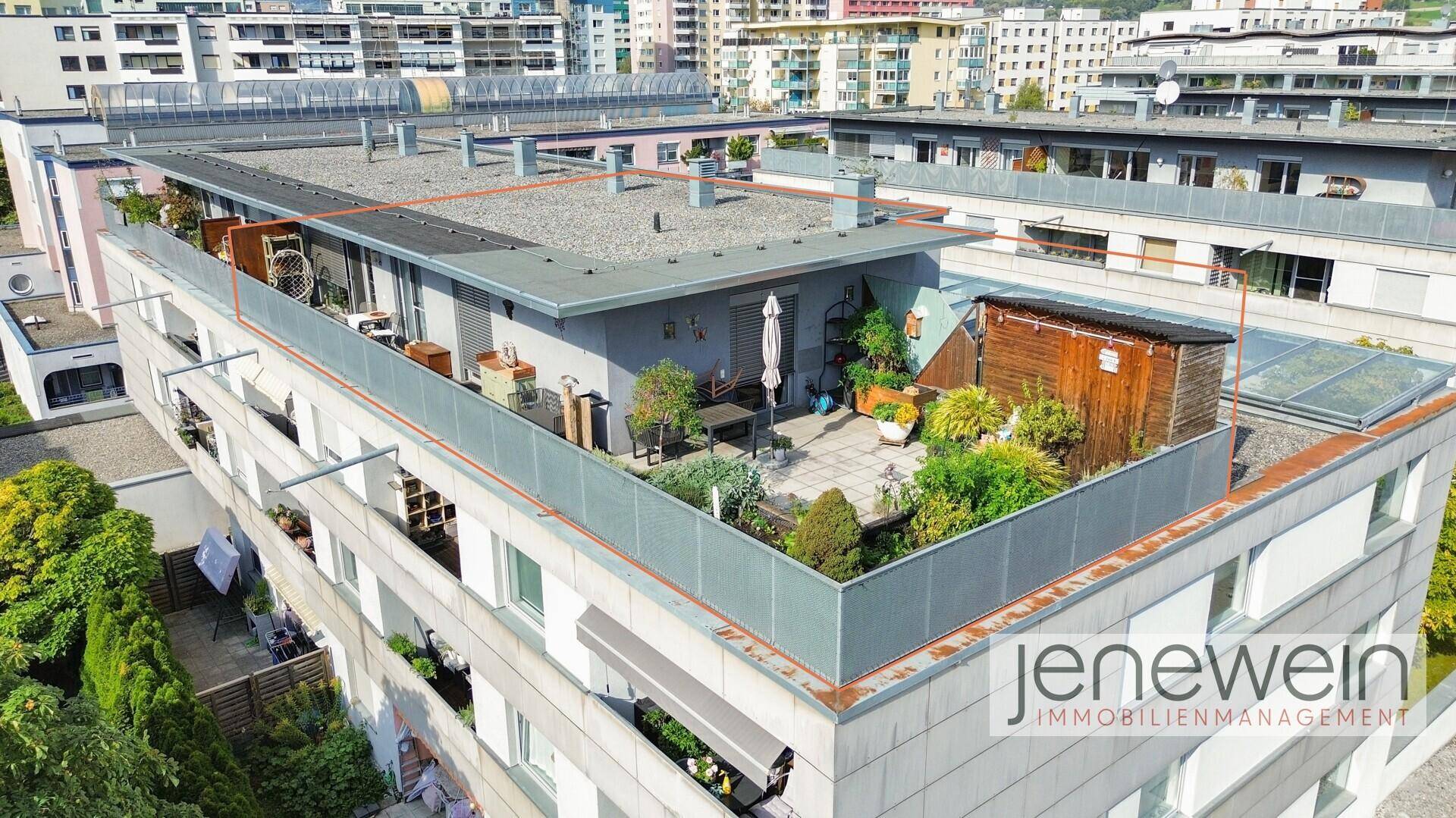 Luftaufnahme eines Wohngebäudes mit Dachterrasse und umliegender Stadtlandschaft.
