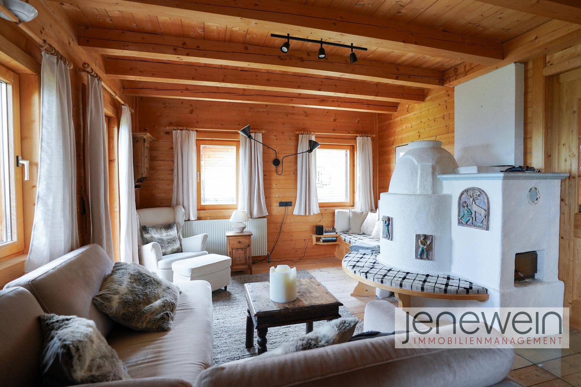 Gemütliches Wohnzimmer mit Kachelofen, Holzbalkendecke und bequemen Sofas.