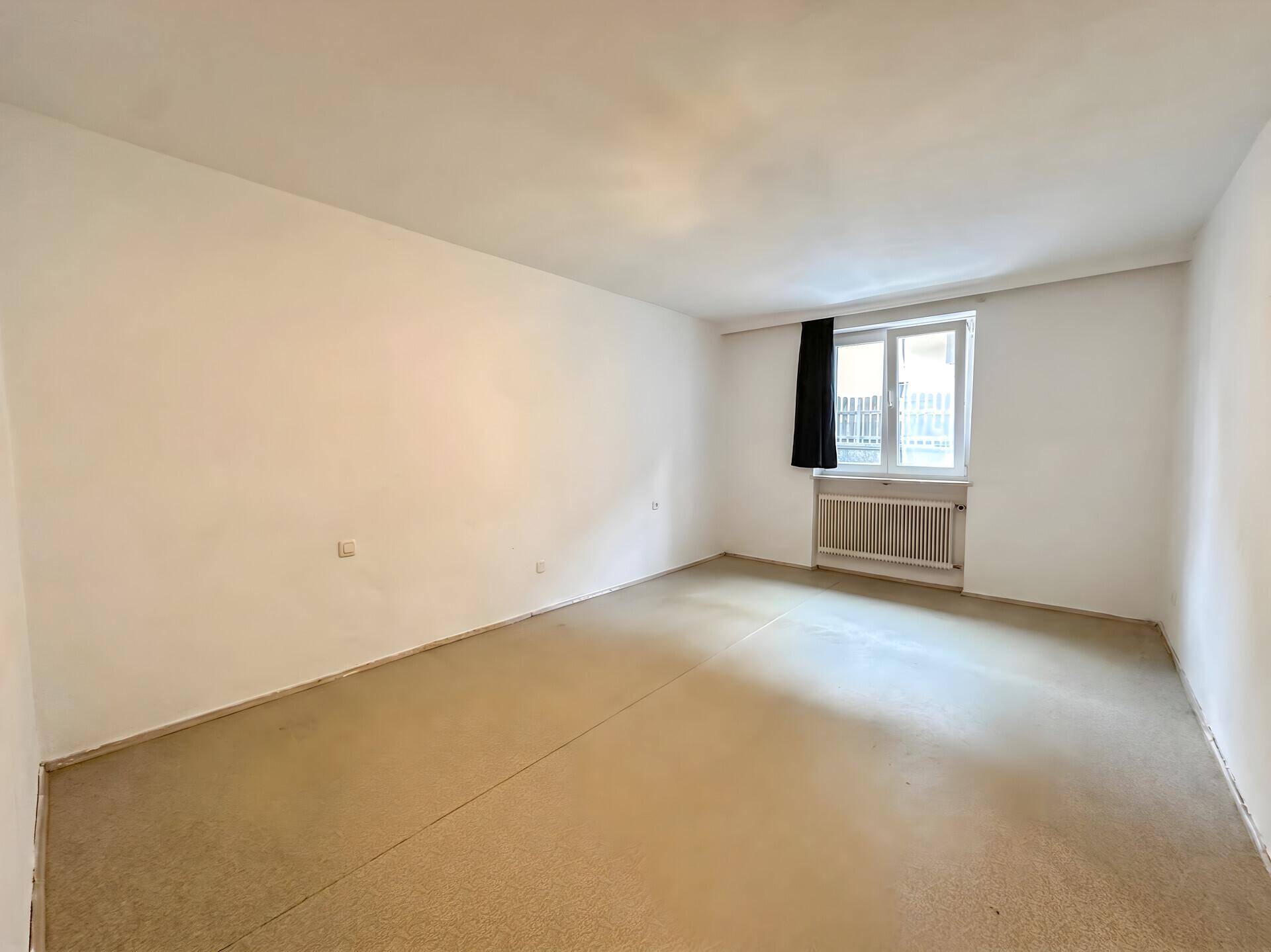 Leeres Schlafzimmer mit hellem Boden und Fenster, bereit zur individuellen Gestaltung.