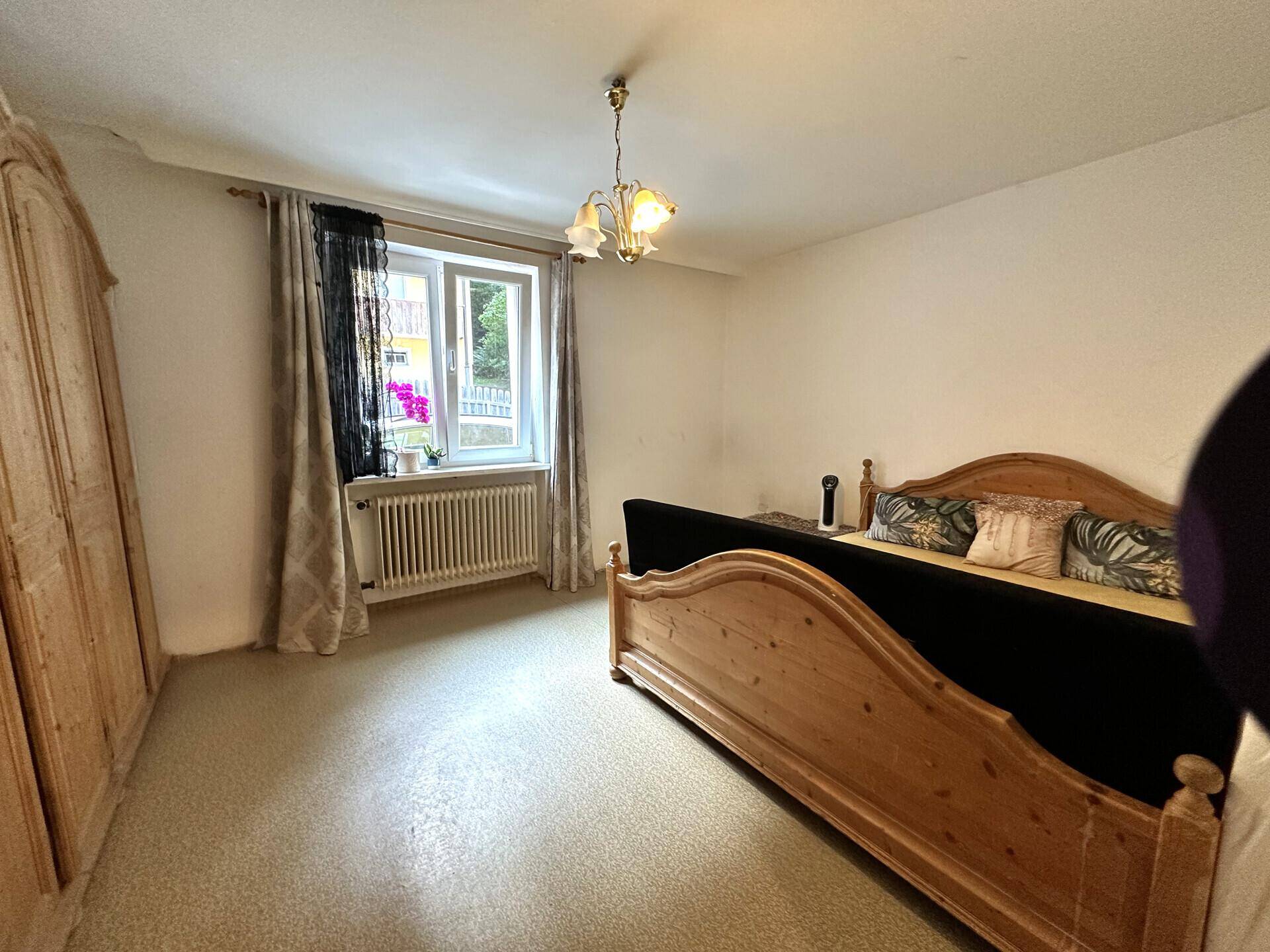 Schlafzimmer mit traditionellen Holzmöbeln, hellem Boden und Fenster.