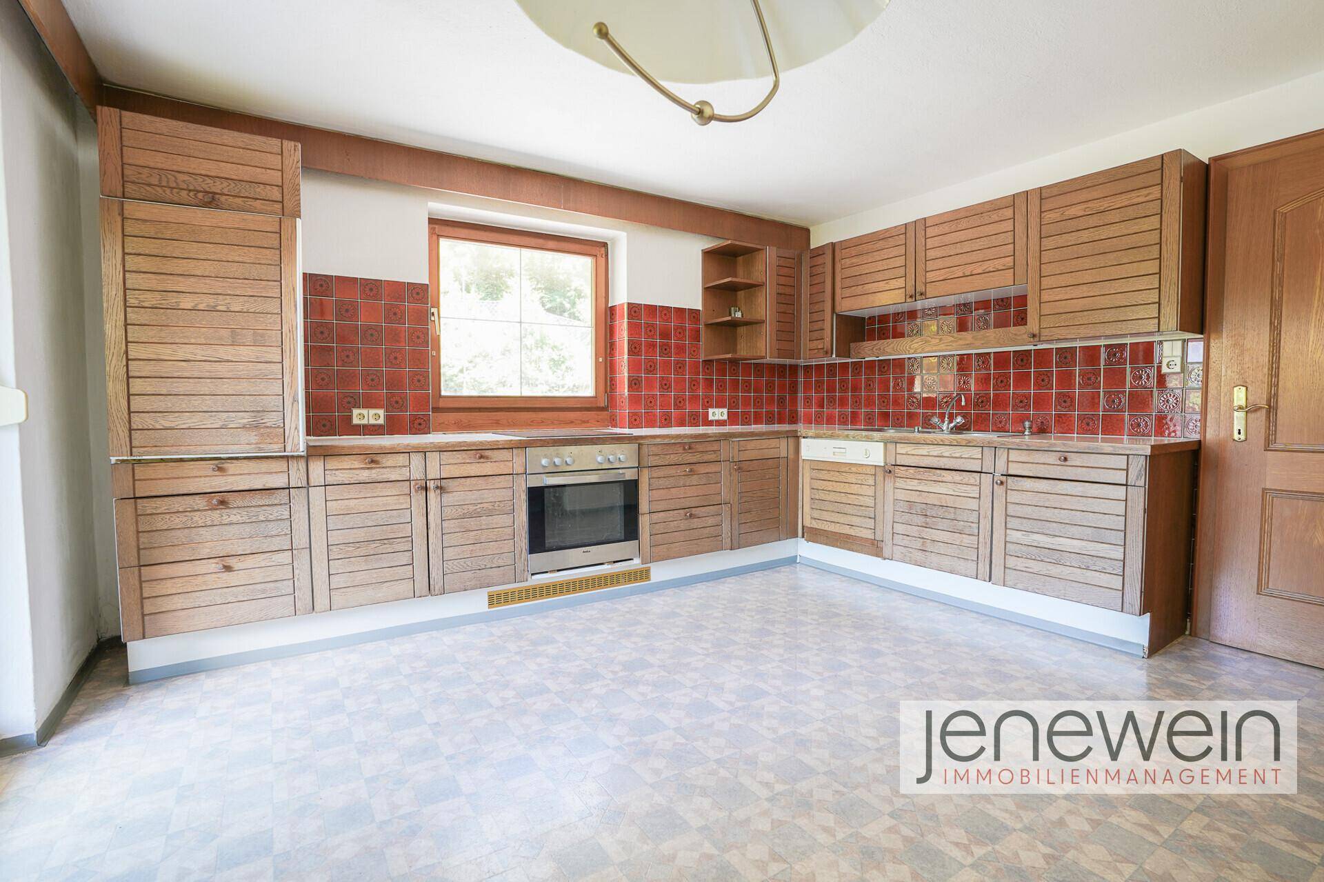 Geräumige Küche mit Holzfronten und roten Fliesen, bereit für individuelle Gestaltung.
