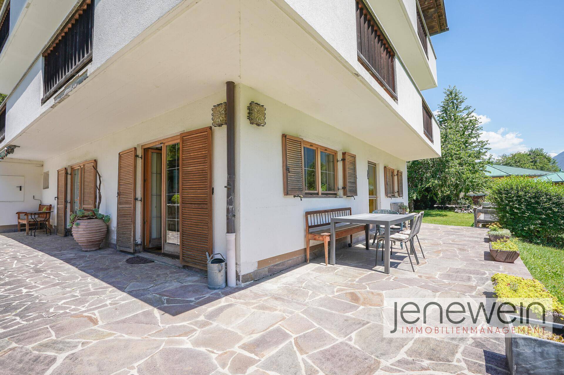 Geräumige Steinterrasse mit Sitzgelegenheiten und Zugang zum Garten, ideal für Mahlzeiten im Freien.