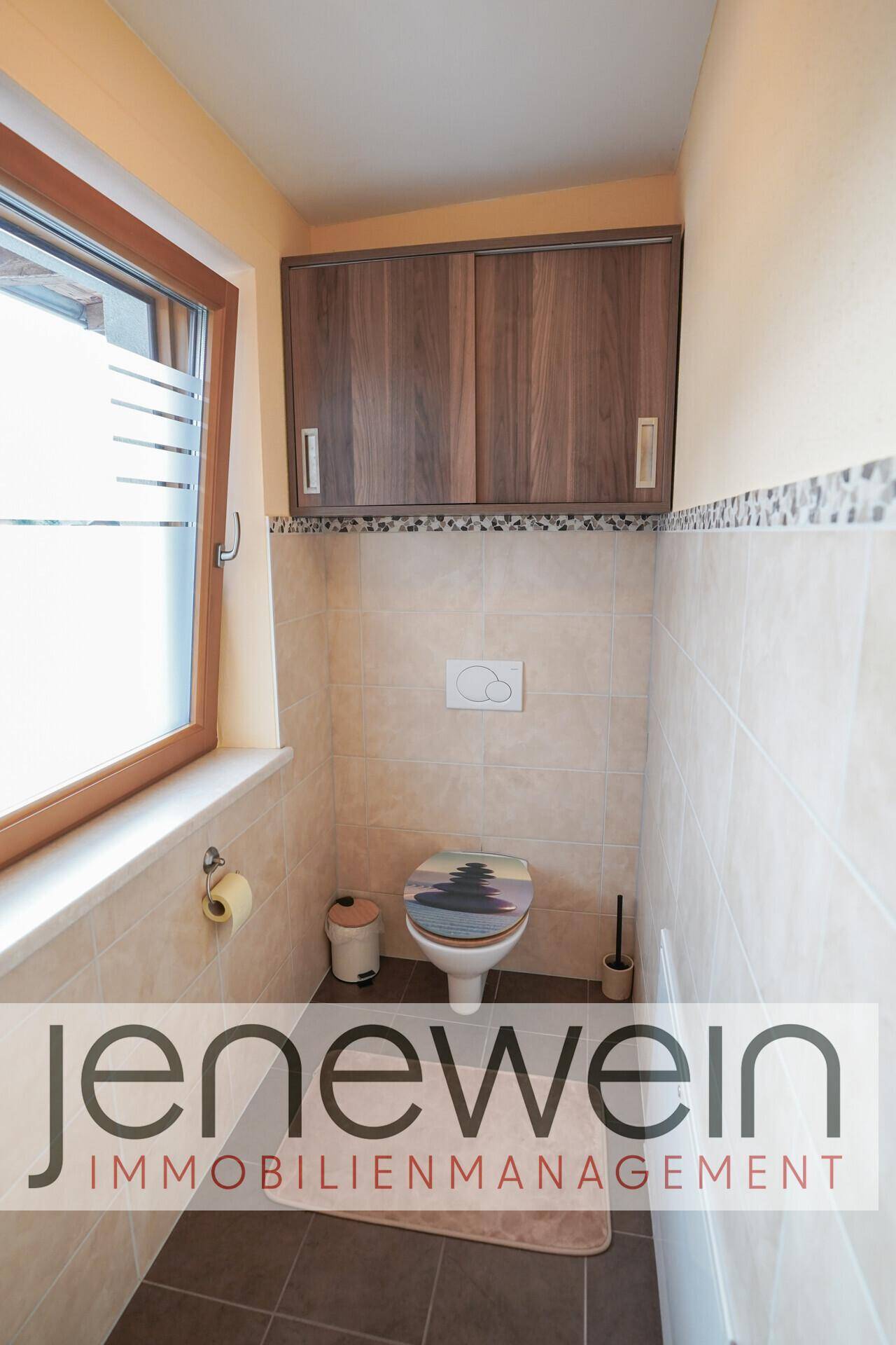 Gäste-WC mit Wand-WC, Spiegelschrank und Fenster für natürliche Belüftung und Helligkeit.