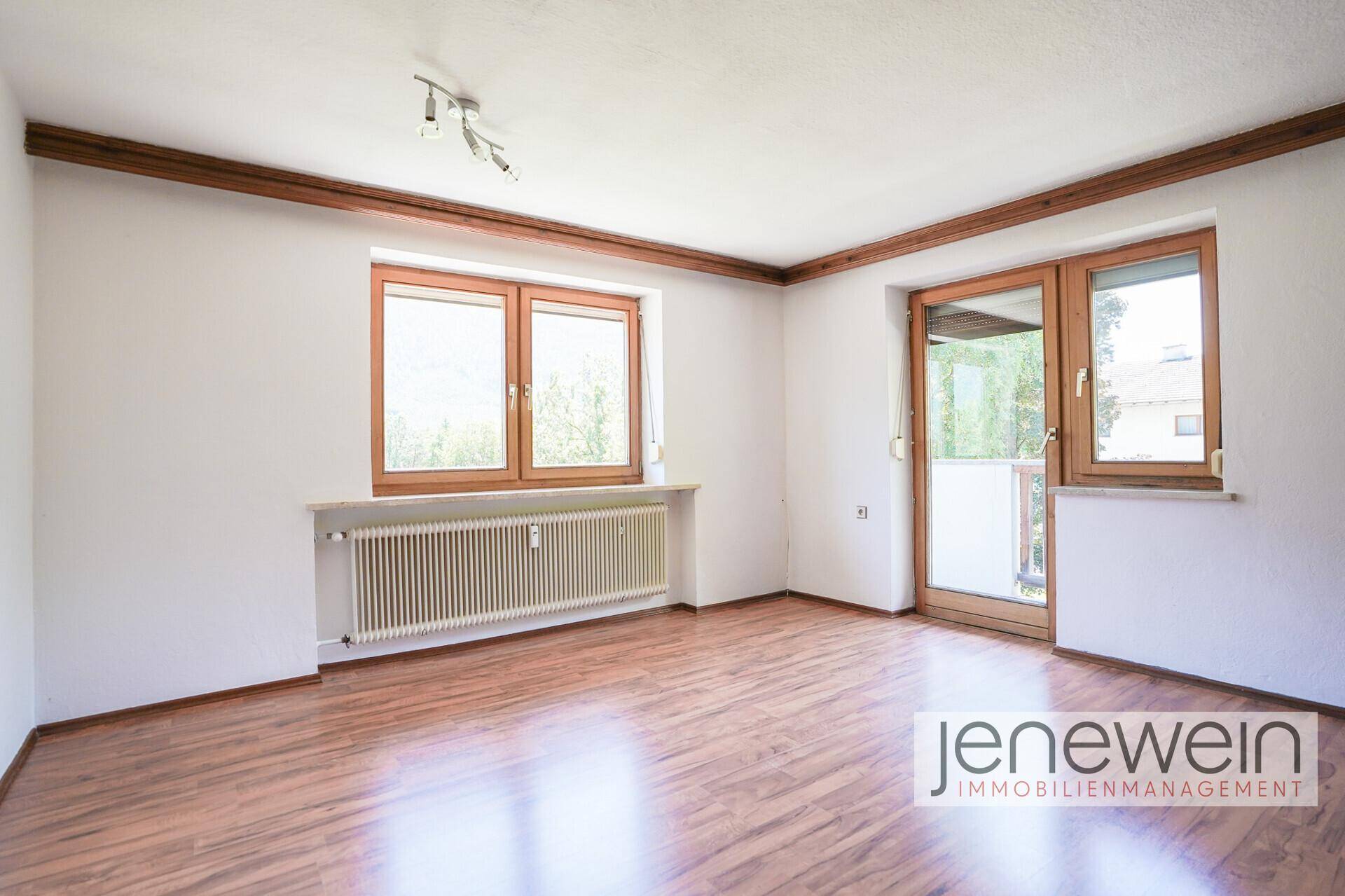 Helles Wohnzimmer mit Laminatboden, Holzbalken und Zugang zu einem französischen Balkon.