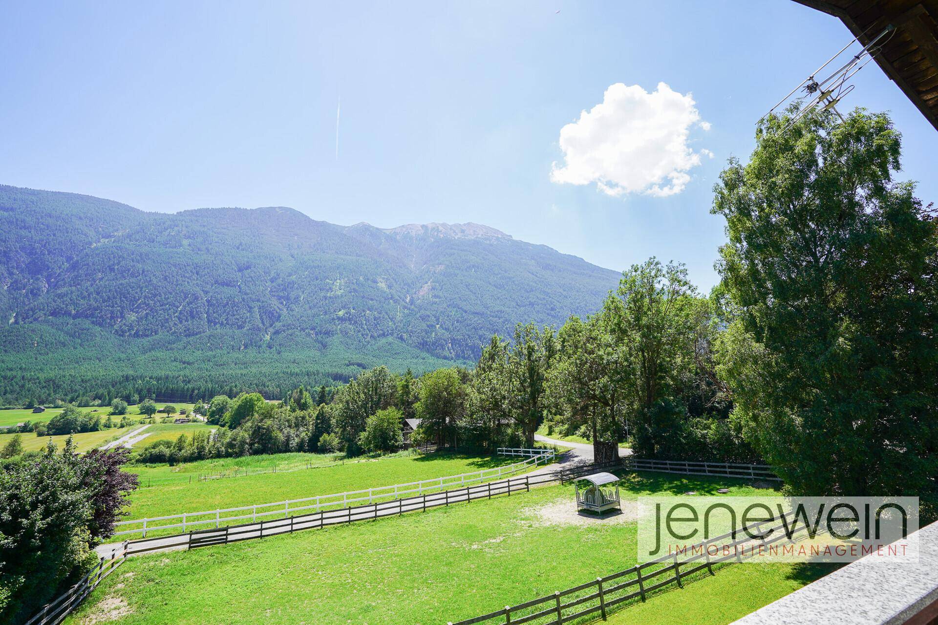 Balkon mit Panoramablick auf weite Wiesen, Wälder und die majestätischen Berge.