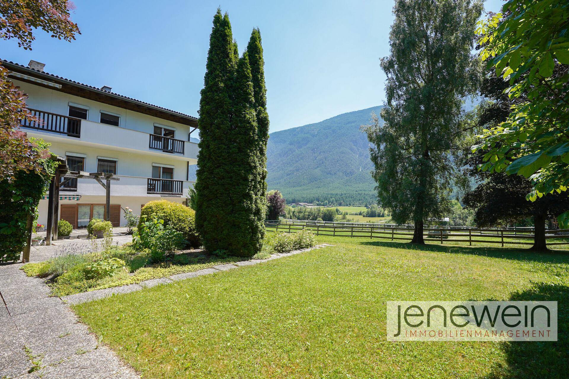 Weitläufiger Gartenbereich mit gepflegtem Rasen und Blick auf die umliegende Natur und Berge.