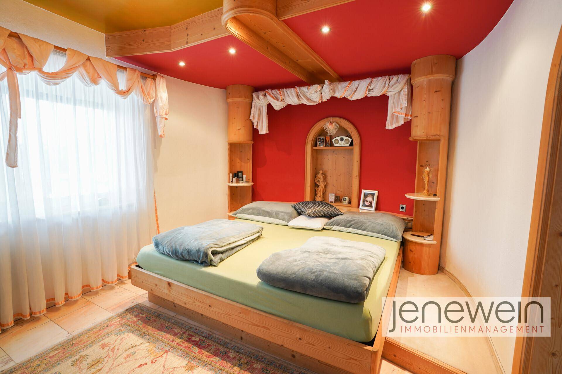 Rustikales Schlafzimmer mit Holzbett, roten Wänden und Holzbalken an der Decke.