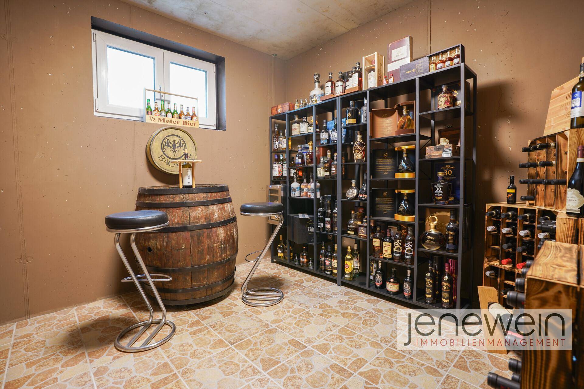 Gemütlicher Weinkeller mit Holzfass-Tisch, Barhockern und umfangreicher Weinsammlung für Liebhaber.