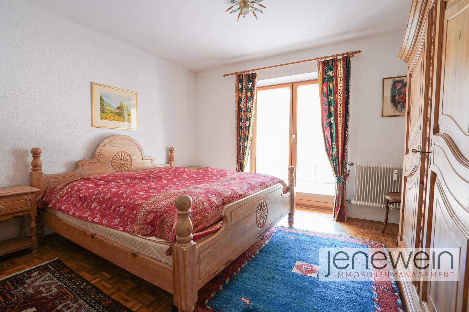 Schlafzimmer mit traditionellem Holzdoppelbett, Kleiderschrank und Zugang zum Balkon.
