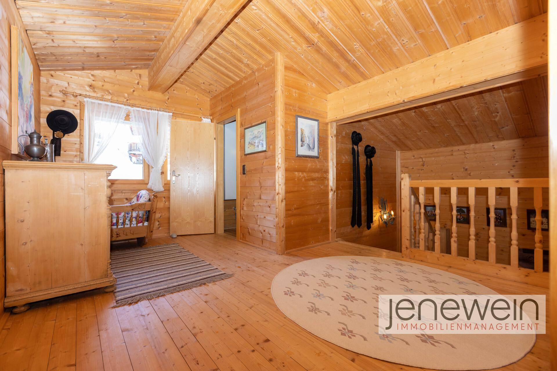 Heller Flur im Obergeschoss mit Holzboden, Holzvertäfelung und Zugang zu weiteren Räumen.