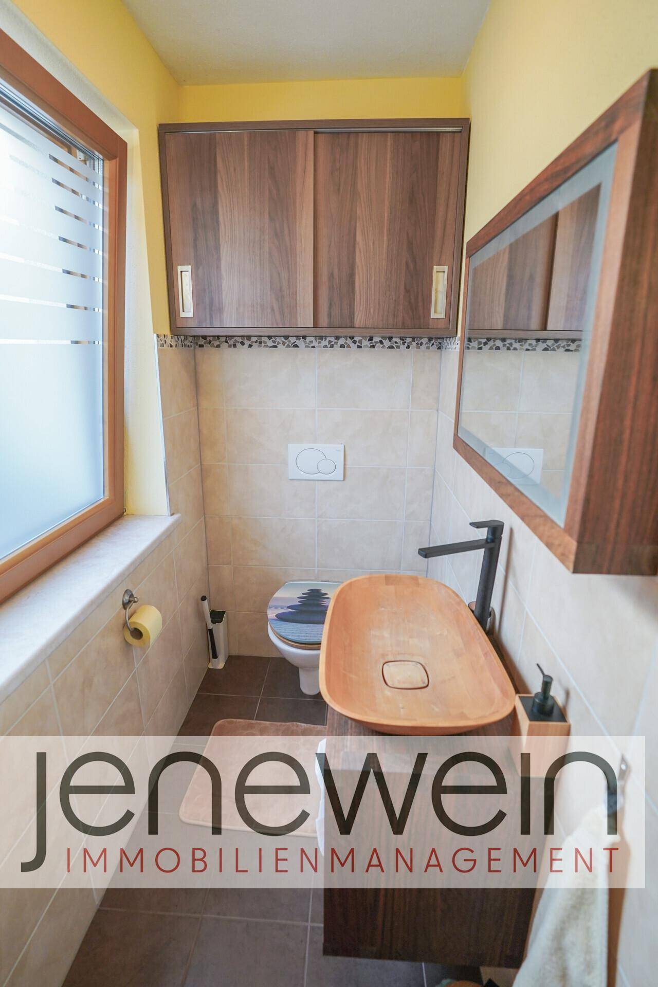Kleines Gäste-WC mit Holzwaschbecken, Spiegelschrank und Fenster für natürliche Belüftung.