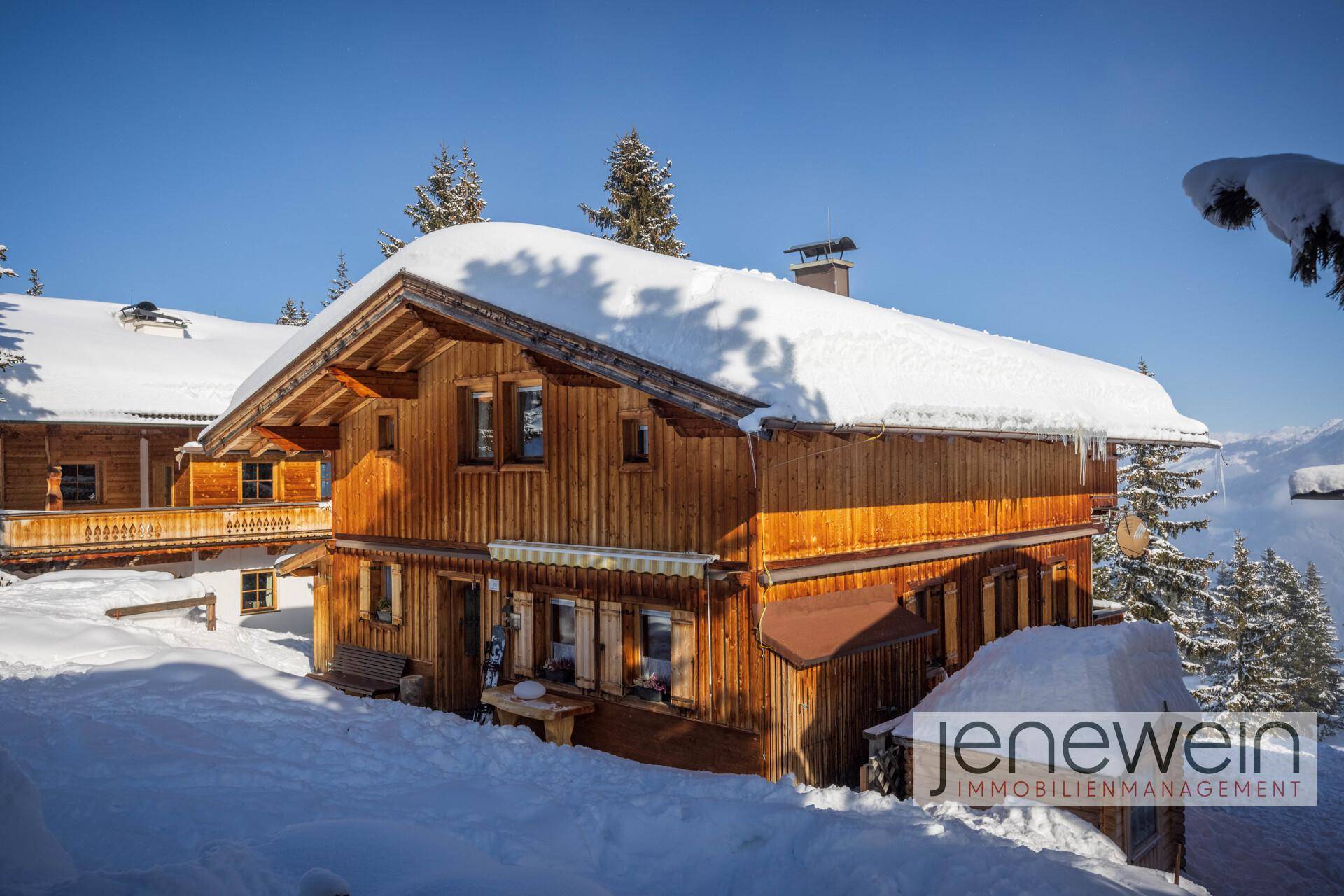 Charmantes Holzchalet mit verschneitem Dach und traditioneller Architektur in den Bergen.