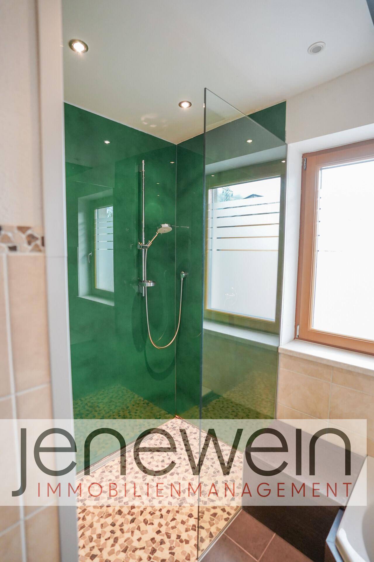 Moderne Duschkabine mit Glaswänden, Regendusche und Fenster im Badezimmer für ein Spa-Erlebnis.