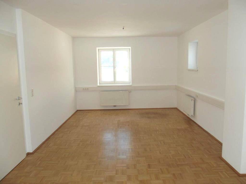 Heller, leerer Raum mit Parkettboden und einem Fenster, ideal für Büronutzung.