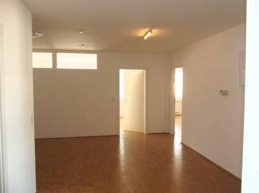 Heller Raum mit Parkettboden und mehreren Türen, die verschiedene Bereiche verbinden.