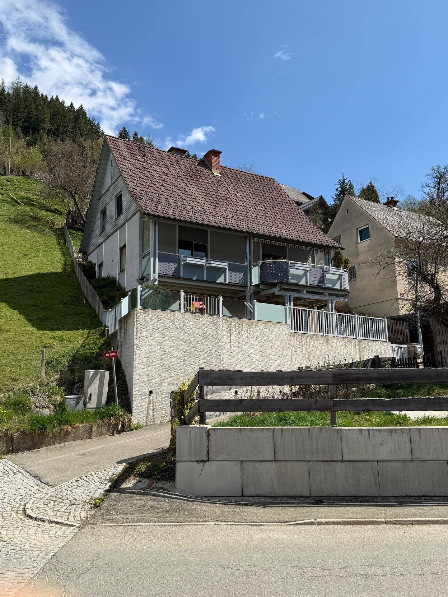 Ansicht des Hauses mit Terrassen und Balkonen, umgeben von grüner Landschaft.