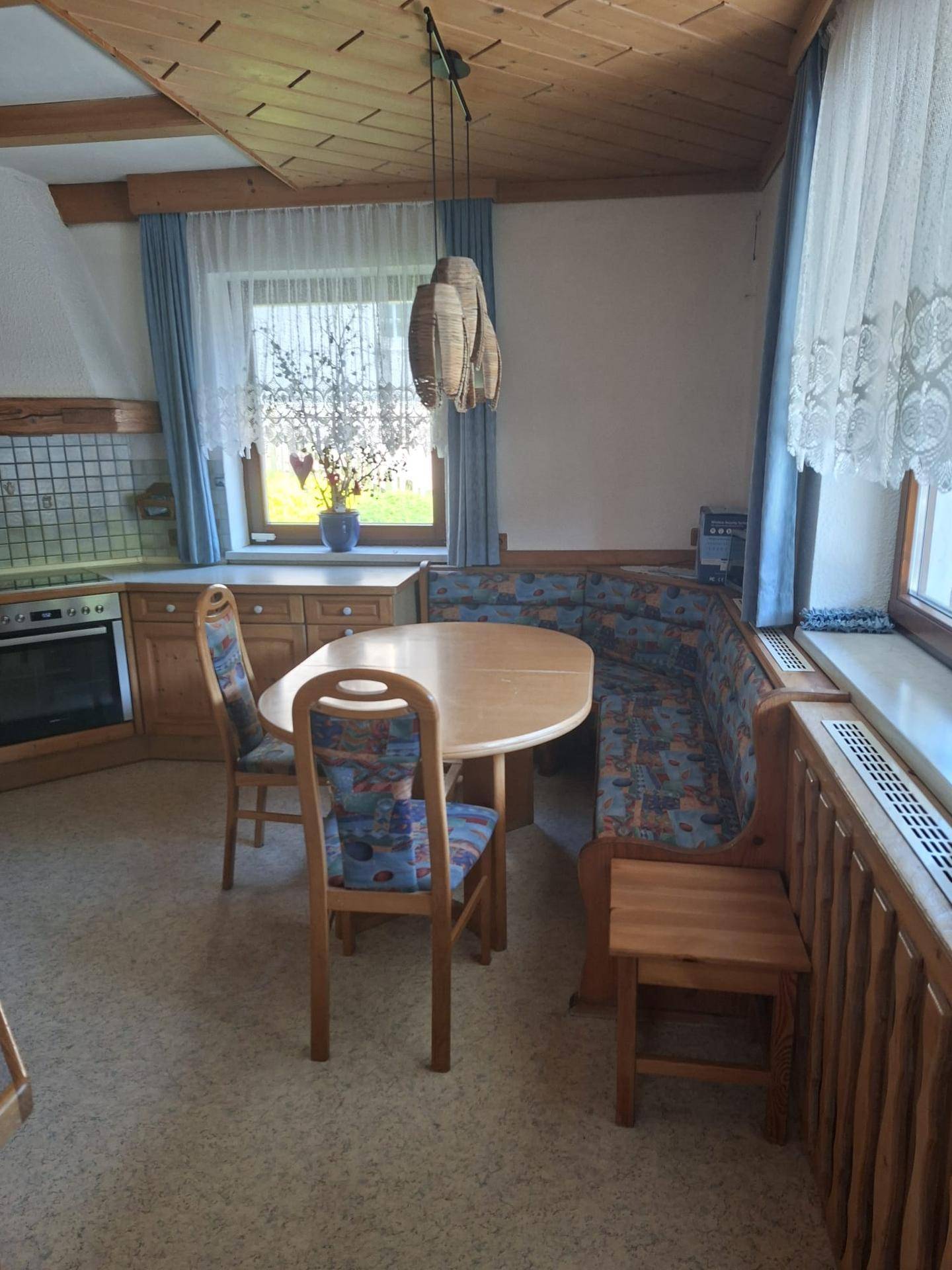 Heller Essbereich mit Holztisch, Eckbank und Blick nach draußen durch die Fenster.