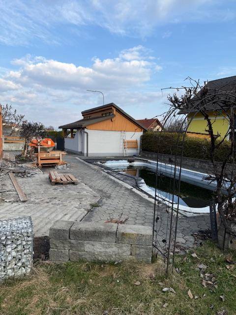 Kleines Nebengebäude mit Holzverkleidung und ein teilweise abgedeckter Pool auf dem Grundstück.
