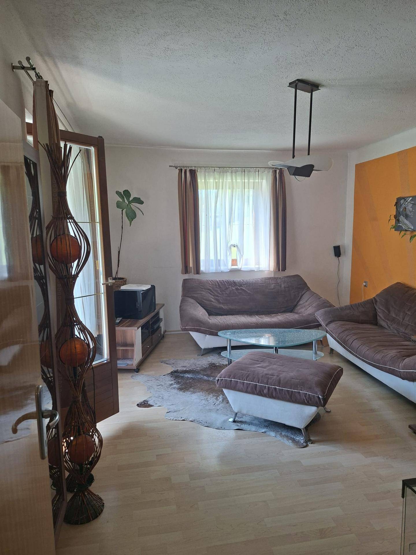 Geräumiges Wohnzimmer mit Holzboden, zwei Sofas und Zugang zu einem Außenbereich.
