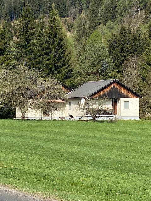 Blick auf das Haus von der Seite, mit traditionellen Holzelementen und umgeben von üppiger Natur.