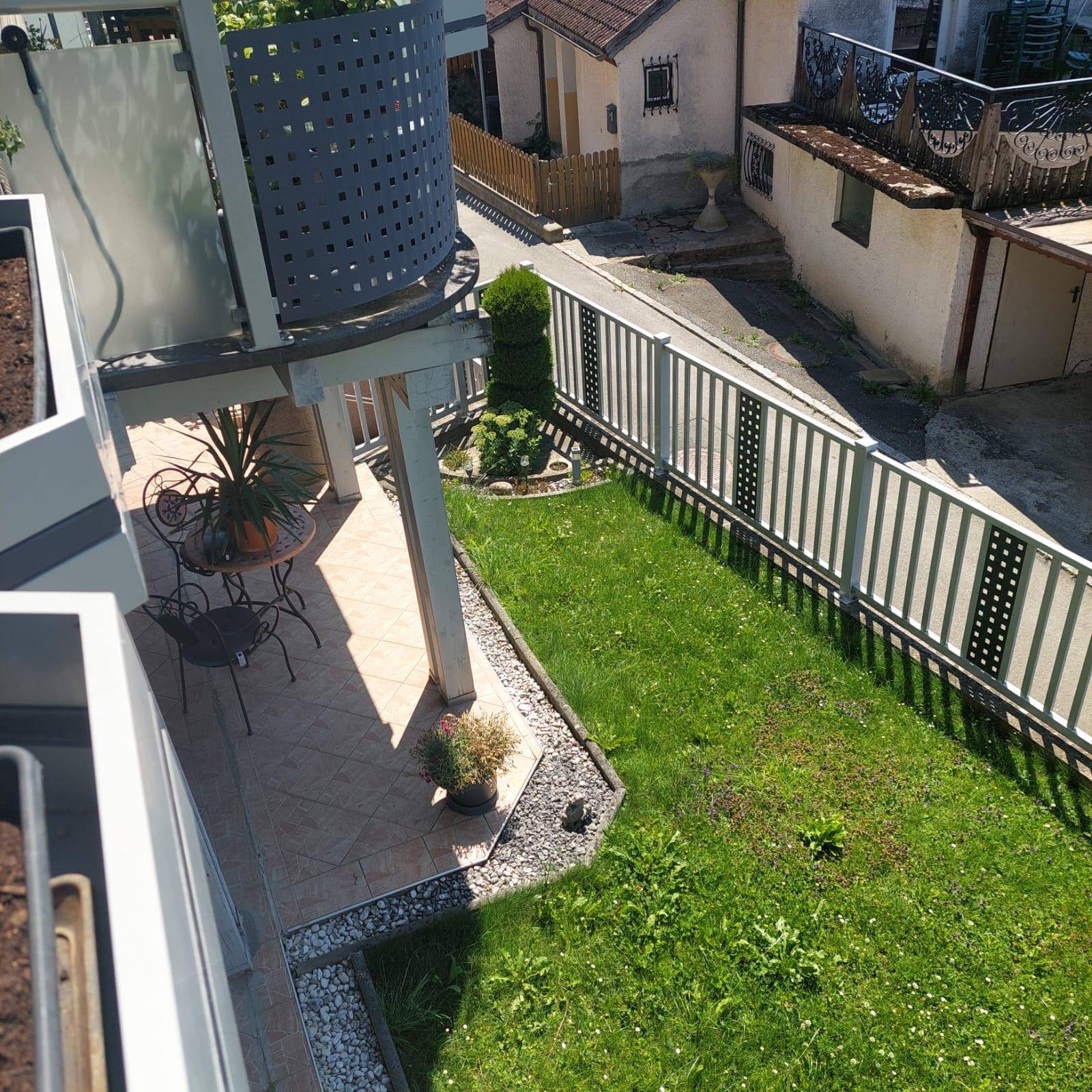 Balkon mit Sitzgelegenheiten und Blick auf einen kleinen Rasenbereich und die Umgebung.