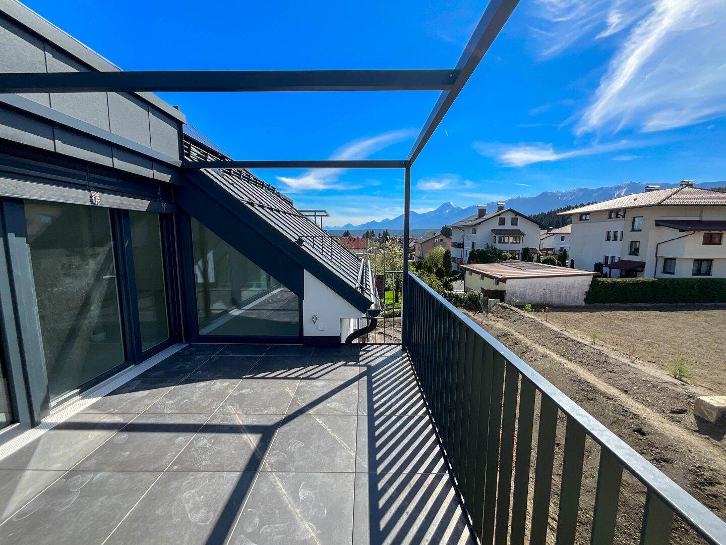 Moderner Balkon mit Fliesenboden und Metallgeländer, bietet einen weiten Blick auf die Berge.