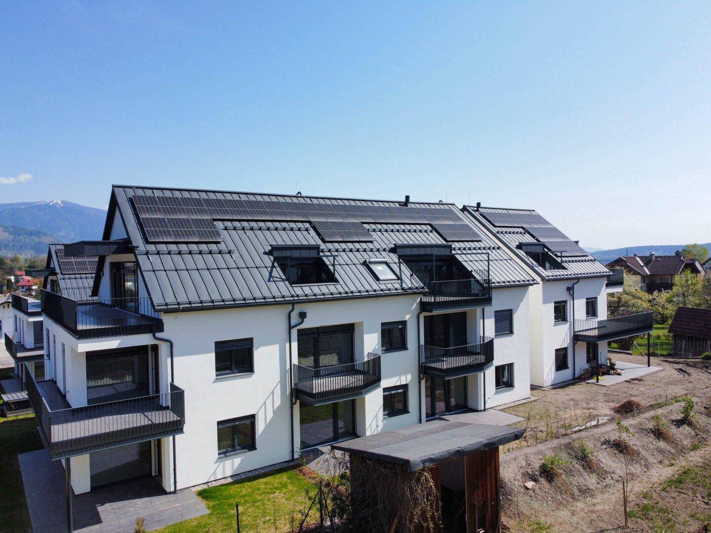 Ansicht der modernen Wohngebäude mit Balkonen, Photovoltaikanlagen und gepflegter Umgebung.