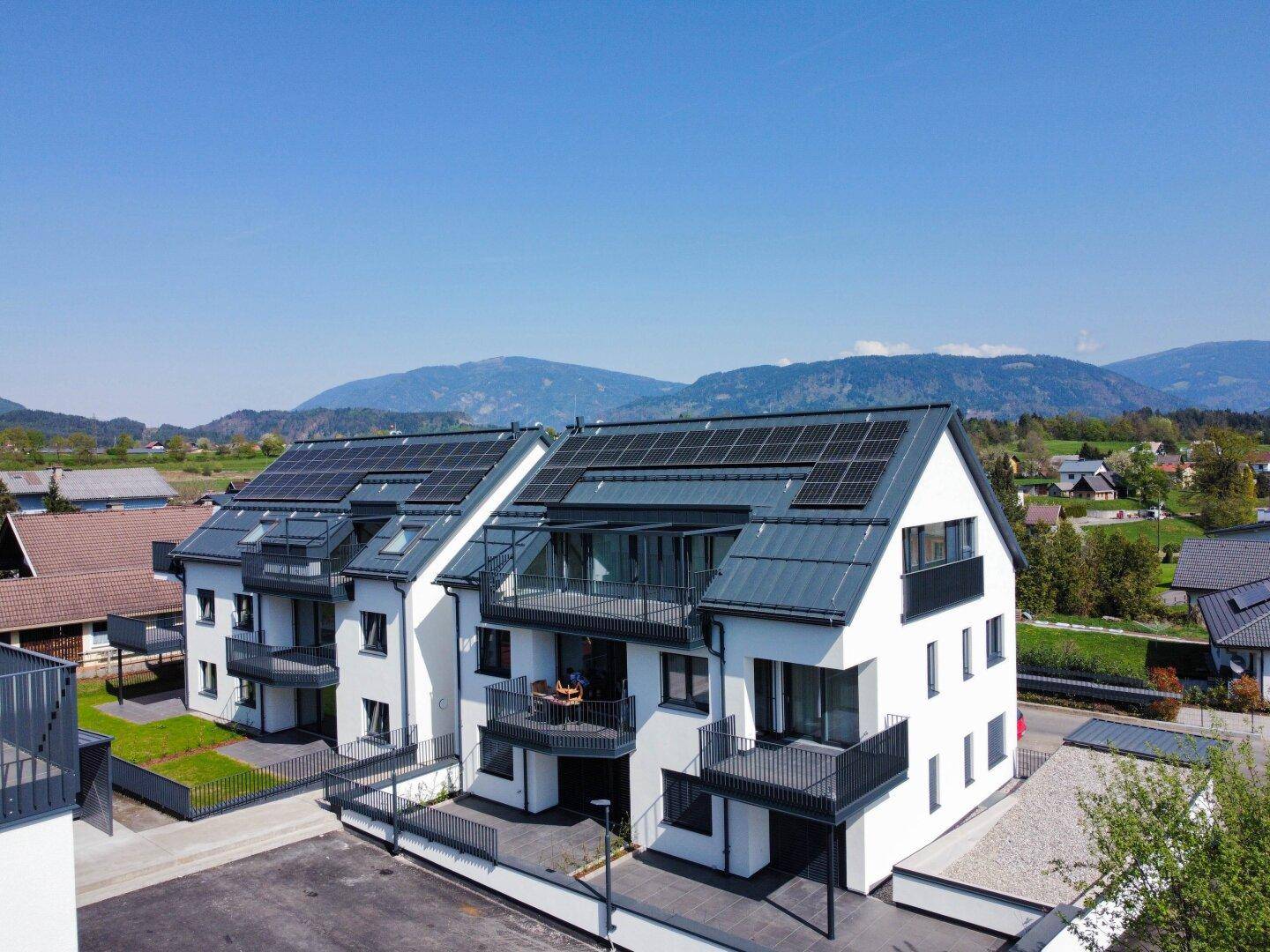 Neubau-Wohnanlage mit zeitgenössischer Architektur, Solaranlagen und weitem Blick auf die Berge.
