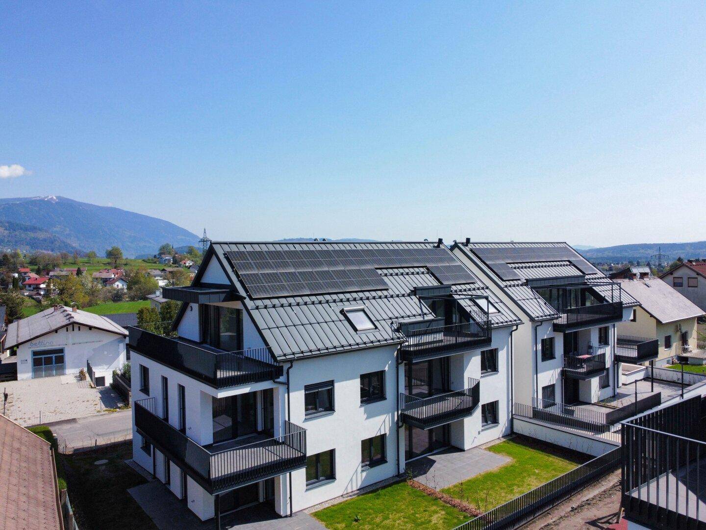 Reihe moderner Wohngebäude mit Solaranlagen auf den Dächern und mehreren Balkonen in sonniger Lage.