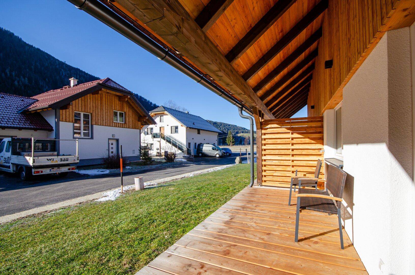 Überdachte Holzterrasse mit Sitzgelegenheiten und Blick auf die umliegende Landschaft.