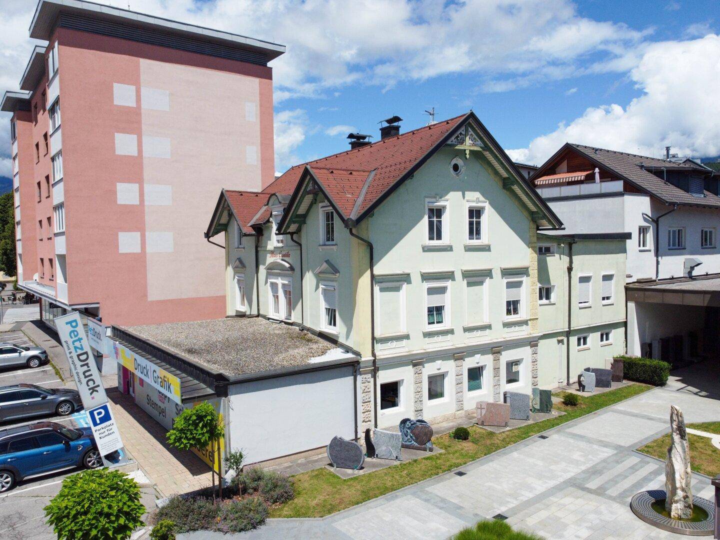 Luftaufnahme des historischen Gebäudes mit angrenzendem Neubau und gepflegter Außenanlage.