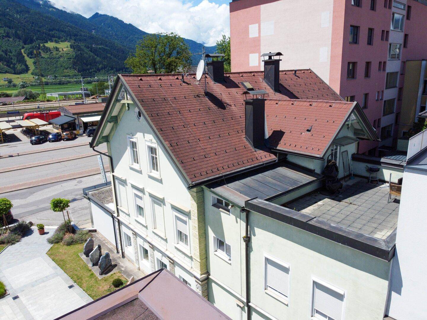 Dachansicht des Gebäudes mit Ziegeln und Schornsteinen, umgeben von Bergen.