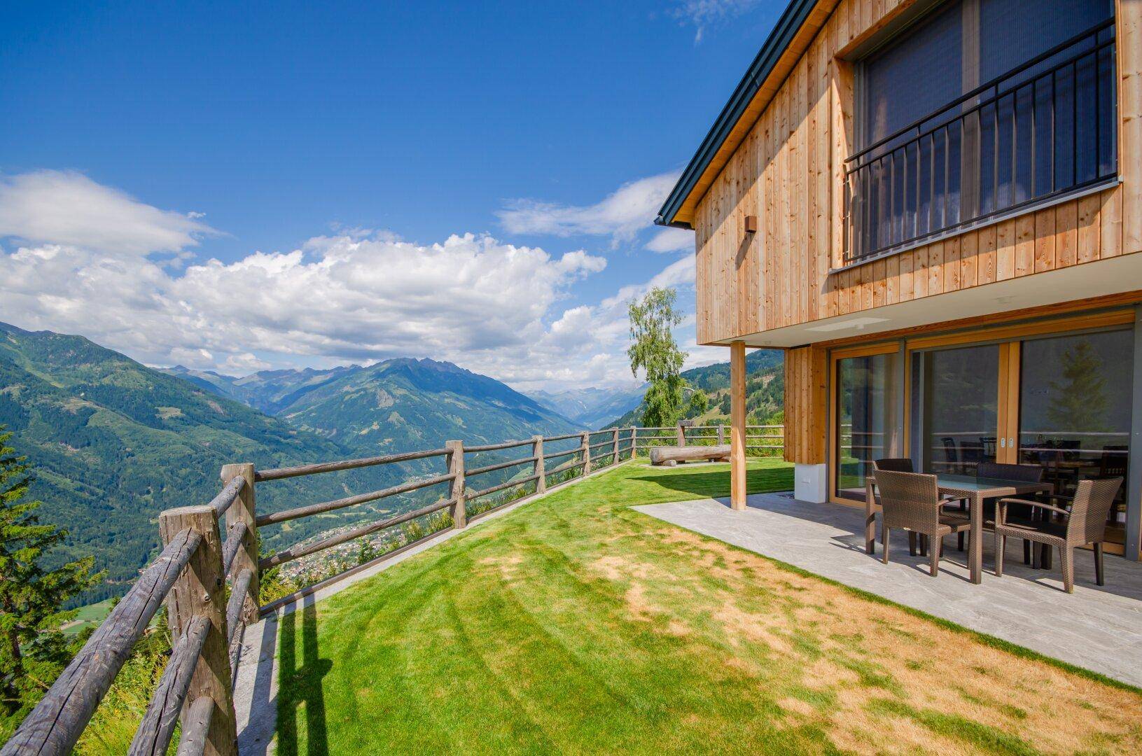 Weitläufige Terrasse mit Rasenfläche und Balkon, bietet einen spektakulären Blick auf die umliegende Bergwelt.