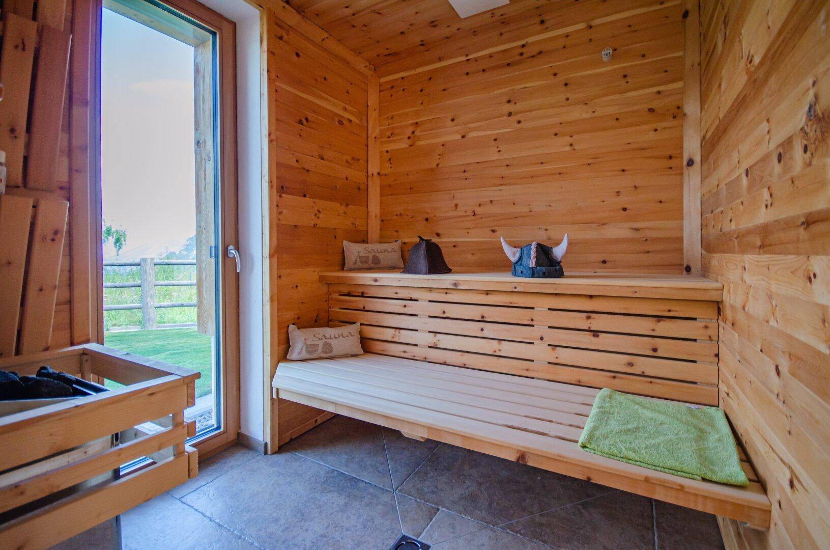 Traditionelle Holzsauna mit Bänken und Blick ins Grüne, ideal zur Entspannung nach einem aktiven Tag.