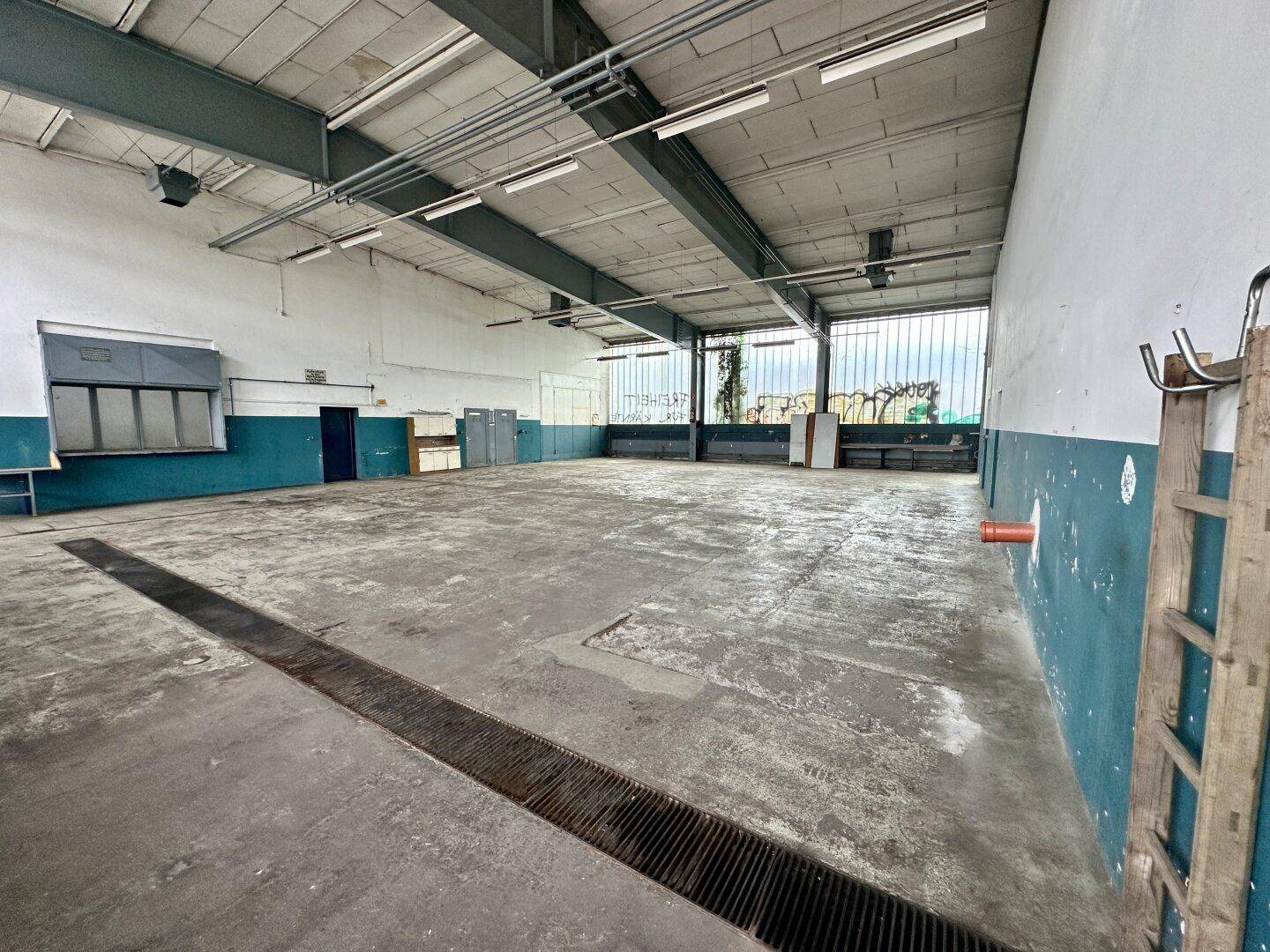 Weitläufige Industriehalle mit Betonboden und sichtbaren Trägern, ideal für Lager oder Werkstatt.