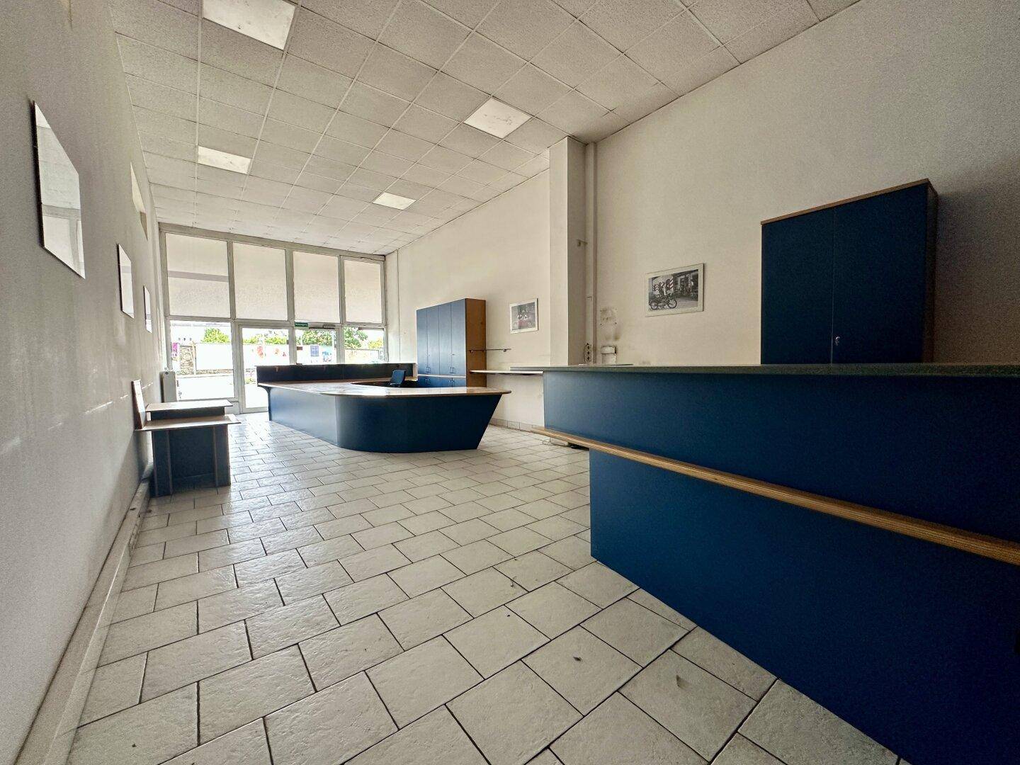 Heller Verkaufsraum mit Fliesenboden und dunklen Theken, geeignet für Empfang oder Kundenbereich.