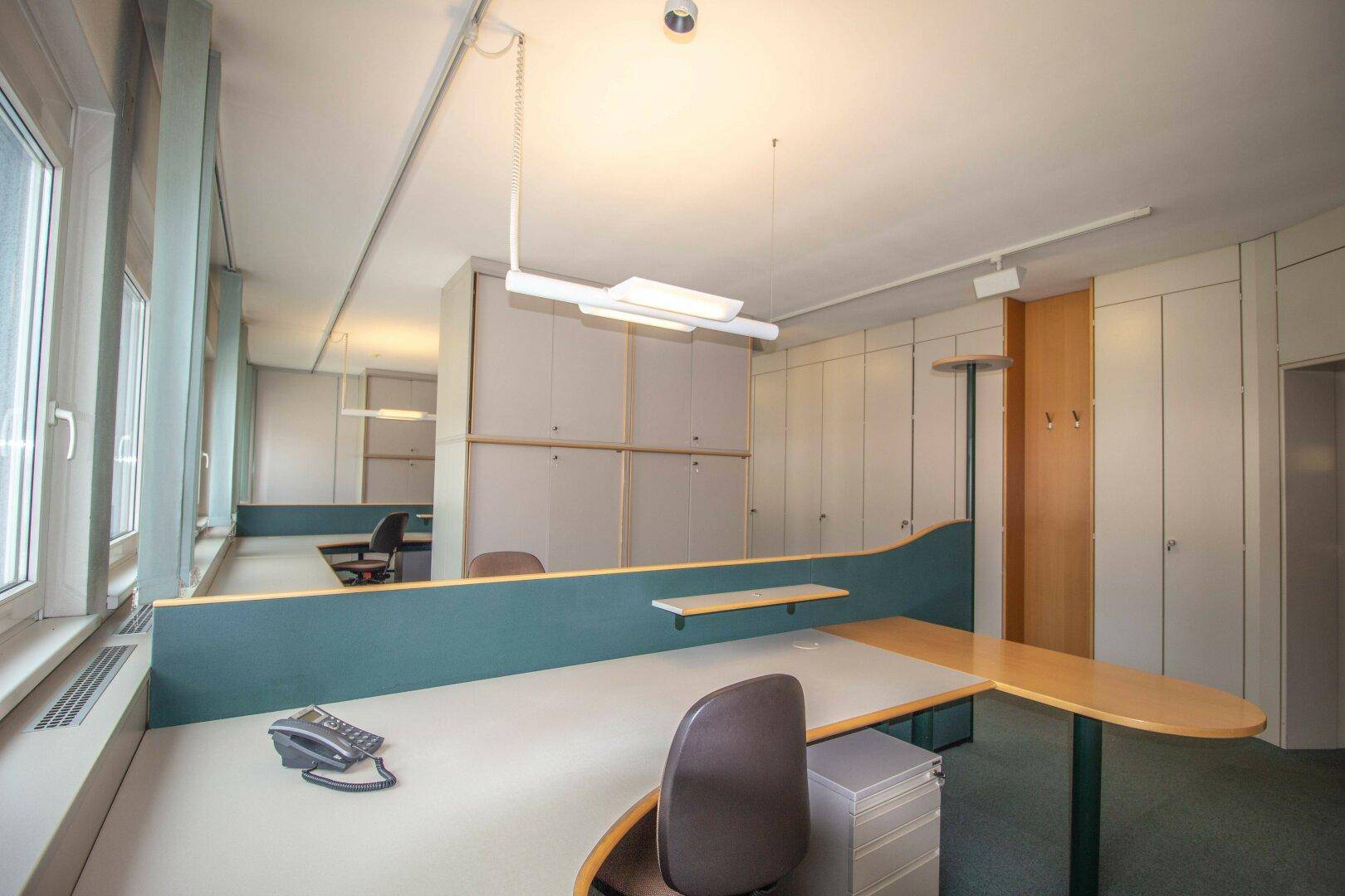 Moderner Arbeitsplatz in einem Großraumbüro mit ergonomischem Schreibtisch und Blick nach draußen.