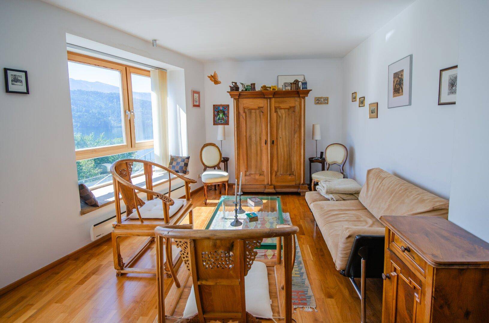 Gemütliches Wohnzimmer mit Holzboden, traditionellen Möbeln und weitem Ausblick durch große Fenster.